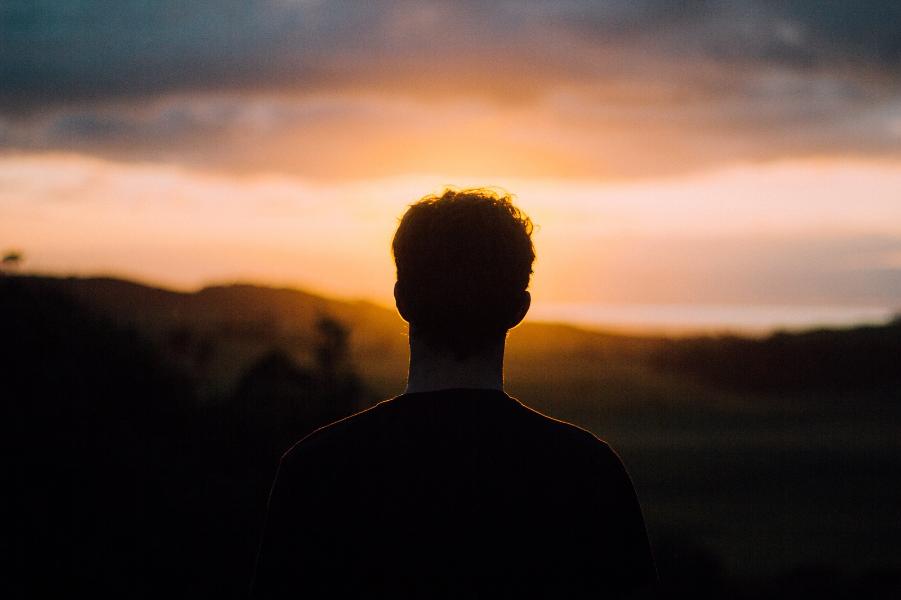 Man looking at hills with a sunset