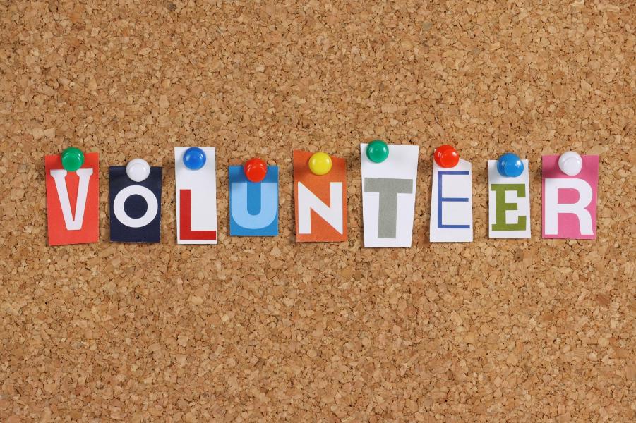 Different colour letter pinned to a pin board spelling volunteer